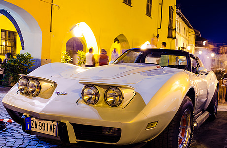 white Chevrolet Corvette C3 coupe parked near white concrete building at night time thumbnail