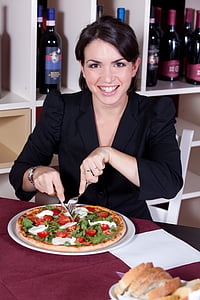 woman in black blazer seating on white chair beside pizza thumbnail