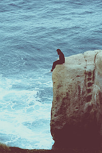 woman sitting on the edge of rock during daytime thumbnail