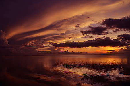 calm sea under orange sky during sunset landscape photography thumbnail