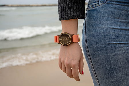 person wearing round black analog watch with orange strap thumbnail