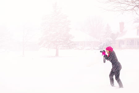 Woman in Pink Hijab Holding Black Dslr Camera Under Raging Snow during Daytime thumbnail