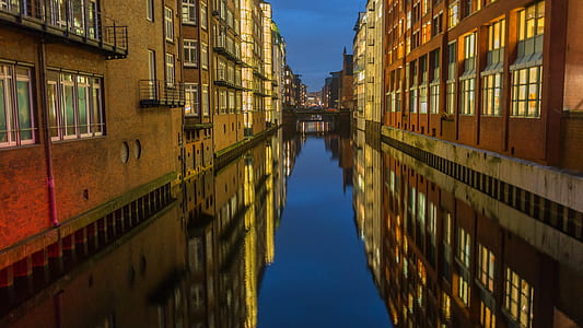calm water between concrete buildings at night time thumbnail