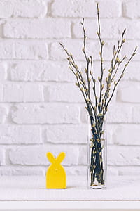 clear glass vase with twigs decor beside yellow rabbit-themed stande thumbnail