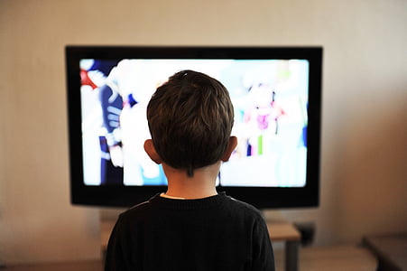 boy standing in front TV turned on thumbnail