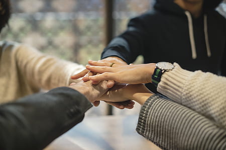 four people placing hands together thumbnail