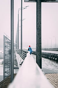 person walking on gray bridge taken at snowtime thumbnail