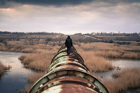 person walking on top of green metal pipe thumbnail