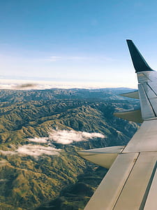 photo of airplane flying above green mountains thumbnail