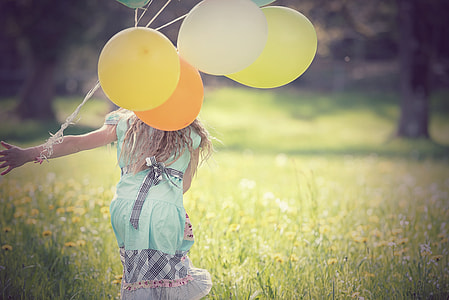 girl with balloons on her left arm about to run on field of flowers thumbnail