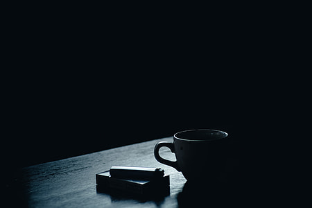 black disposable lighter on white cigarette box beside white ceramic mug placed on black wooden table thumbnail