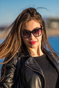 shallow focus photography of woman in black leather full-zip jacket wearing sunglasses thumbnail