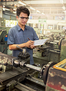 man holding brown clipboard in front of industrial machine thumbnail
