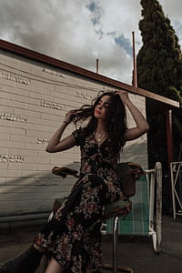 woman holding her hair while sitting on white chair thumbnail