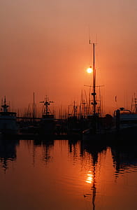 Fishing boats tied up to the dock as sunset in the background over an ocean thumbnail