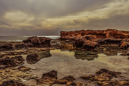 body of water beside rock formation thumbnail