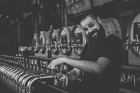 grayscale of smiling man on beverage dispenser thumbnail