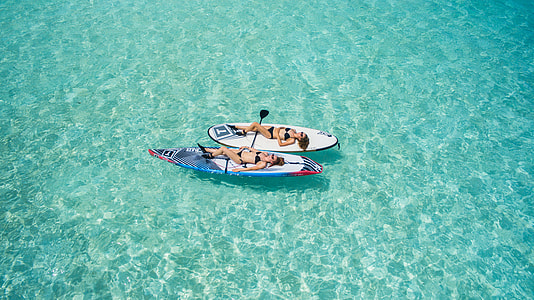 aerial photography of two women lying on paddle boards thumbnail