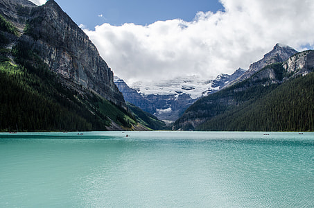calm body of water in between mountainous terrain under white skies thumbnail