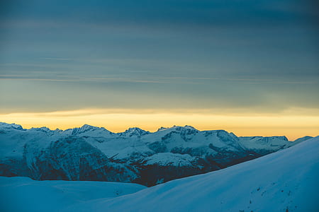 white and black mountains under brown and gray sky at golden hour thumbnail