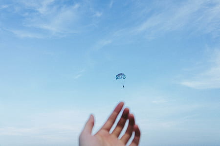 person focusing his hand on person parachuting thumbnail