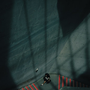 aerial photography of woman sitting on grey floor beside grey wall inside the building thumbnail