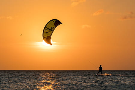 person parasurfing on body of water during golden hour thumbnail