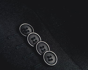 close-up photo of four black shirt buttons thumbnail