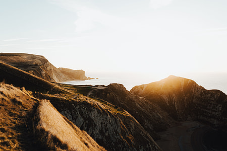 brown mountain near body of water during golden hour thumbnail