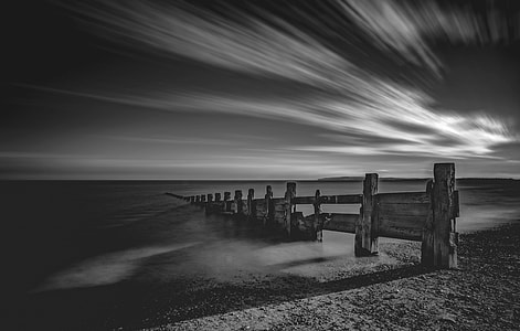 grayscale photography of brown wooden dock under clouds thumbnail