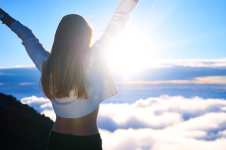 woman wearing white bolero lifting her arms wide-open while looking on white clouds and blue sky during daytime thumbnail