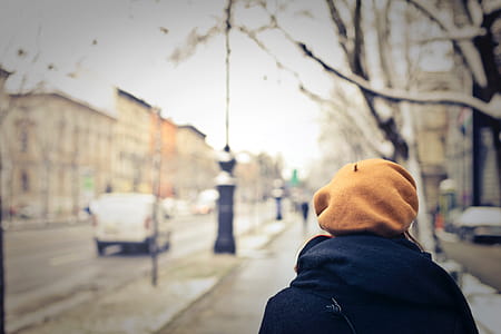 A woman wearing an orange cap walking on the sidewalk on a winter day thumbnail