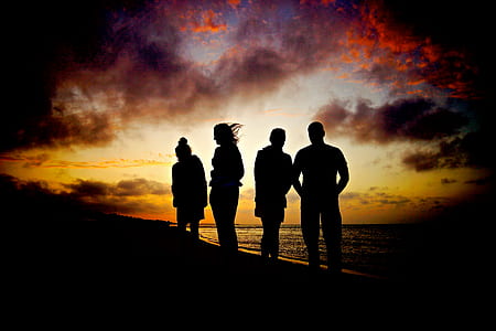 silhouette of four people standing near seashore towards sunset view thumbnail