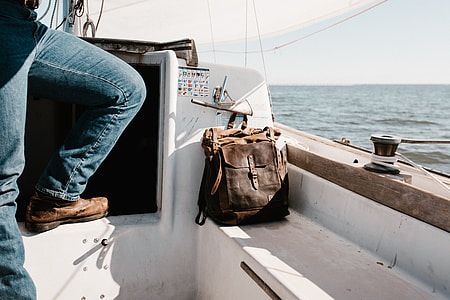 brown leather knapsack in white speedboat beside a person thumbnail