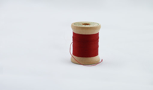 red thread spool on white surface thumbnail