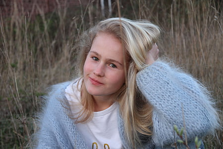 woman wearing blue knitted sweater and white crew-neck shirt holding her head thumbnail
