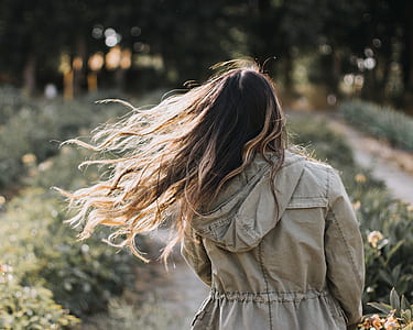 woman gray hooded jacket walking near green plant thumbnail