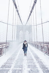 woman in jacket standing in the middle of bridge during snow thumbnail