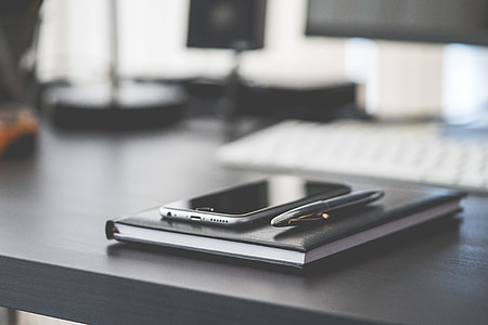 Smartphone, Diary and Silver Pen on Black Workspace Desk thumbnail