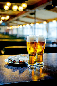 fish dish on saucer beside beer-filled glasses on table thumbnail