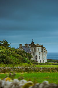 white and gray painted castle near green grass fields under cloudy sky thumbnail