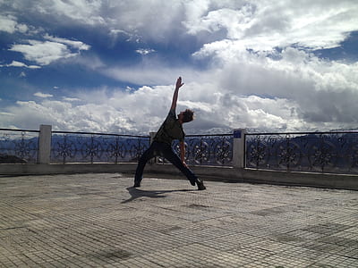 person bending feet and arm on building roof under cloudy sky thumbnail