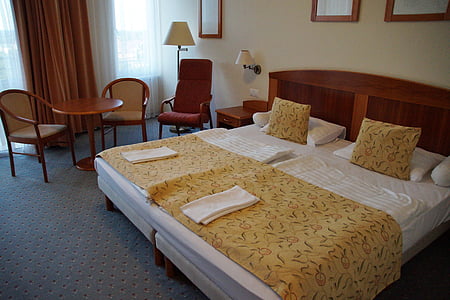 yellow and whote bedspread beside armchairs near window thumbnail