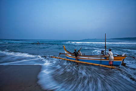 three men pushing canoe on sea during daytime thumbnail