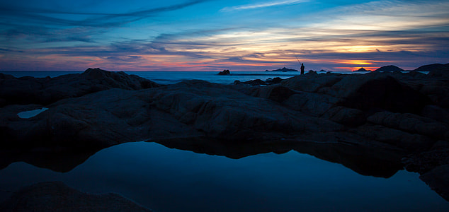 silhouette of mountain near body of water thumbnail