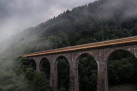 gray concrete bridge near mountain during daytime thumbnail