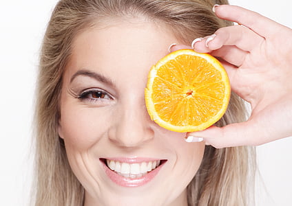 woman with brown hair holding sliced orange thumbnail