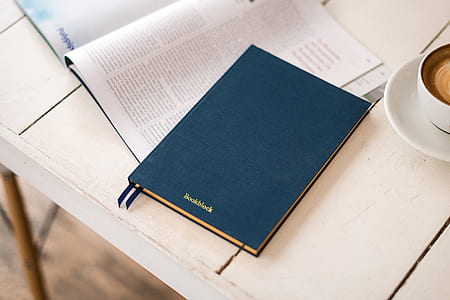 blue hardbound book beside cup of coffee late on white wooden table thumbnail