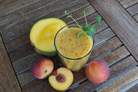 clear glass cup filled with peach shake beside peach fruits thumbnail