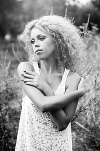grayscale photography of woman wearing sleeveless top standing near plant thumbnail